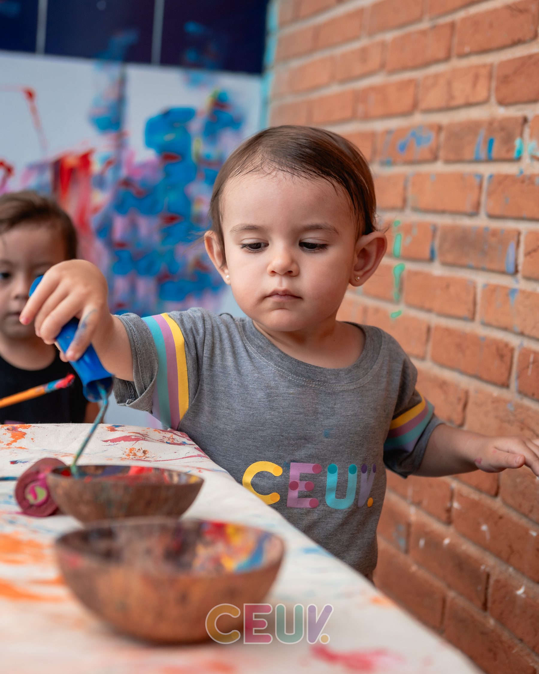 Criança do CEUV explorando tintas coloridas